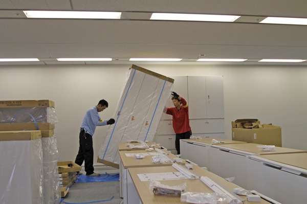 新規家具・備品 組立設置作業②<br>内装工事が完工した事務所に新しい家具が運び込まれ、次々と設置されていきます。 こちらでは、明るい木目の大型天板（ワークテーブル）を納めさせていただきました。